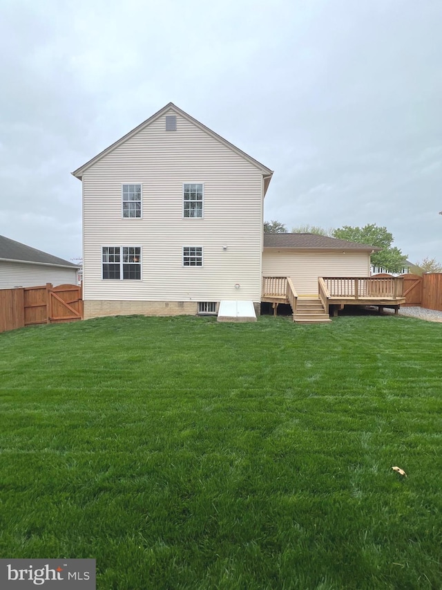 rear view of property featuring a yard, fence, a deck, and a gate