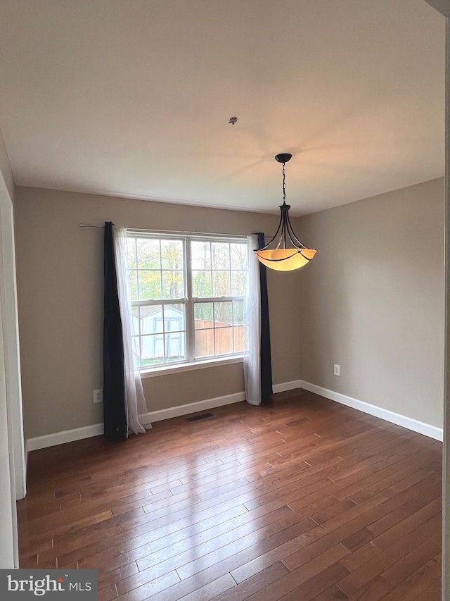 unfurnished room featuring visible vents, baseboards, and dark wood-style floors