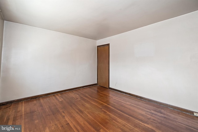 unfurnished room with baseboards and dark wood-style flooring