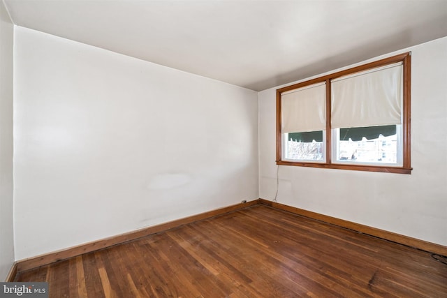 unfurnished room with baseboards and dark wood-style flooring