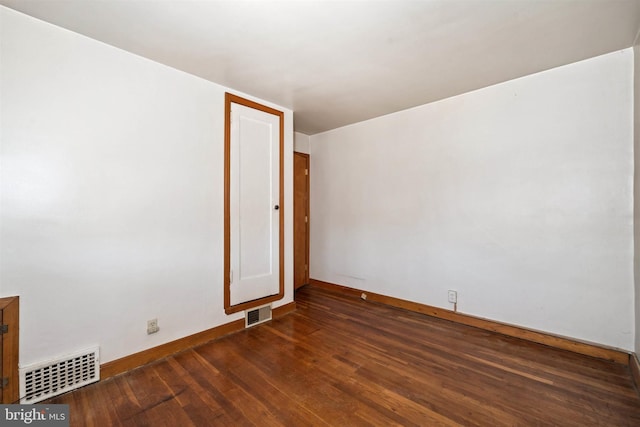 spare room featuring visible vents, baseboards, and wood-type flooring