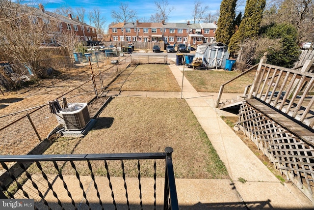 view of yard with an outbuilding, fence, central AC unit, a storage shed, and a residential view