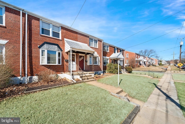 view of property with a residential view, brick siding, and a front lawn