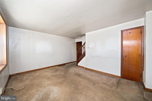 carpeted empty room featuring stairway, baseboards, and visible vents