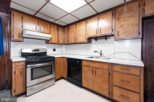 kitchen featuring under cabinet range hood, light countertops, black dishwasher, stainless steel gas range, and a sink