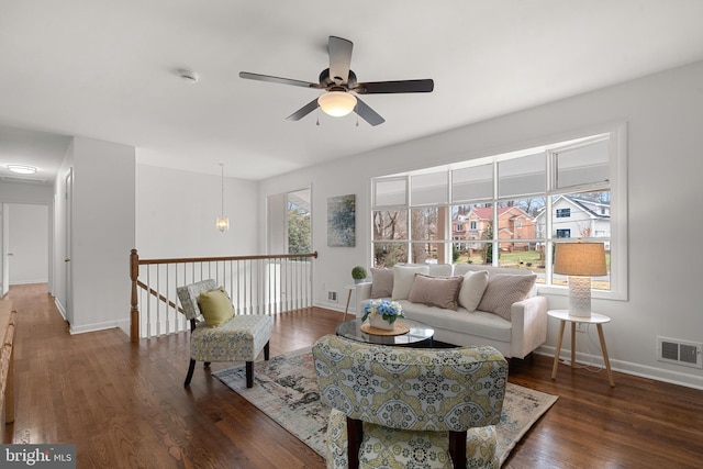 living area featuring visible vents, baseboards, a ceiling fan, and wood finished floors