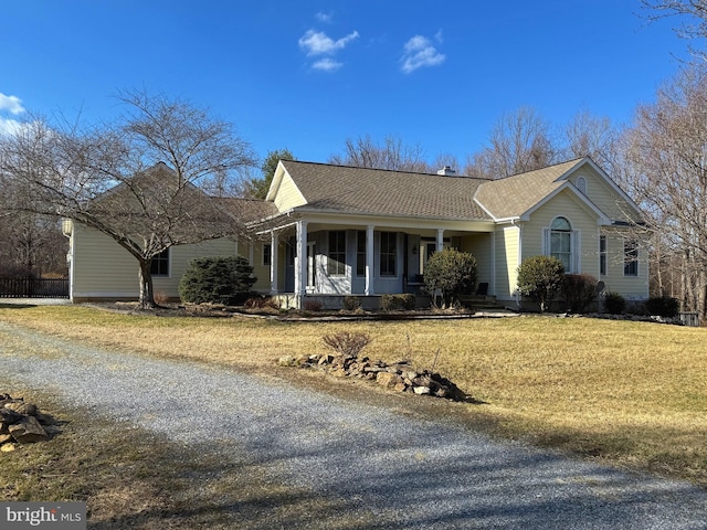 view of front of house with covered porch, driveway, a front lawn, and roof with shingles