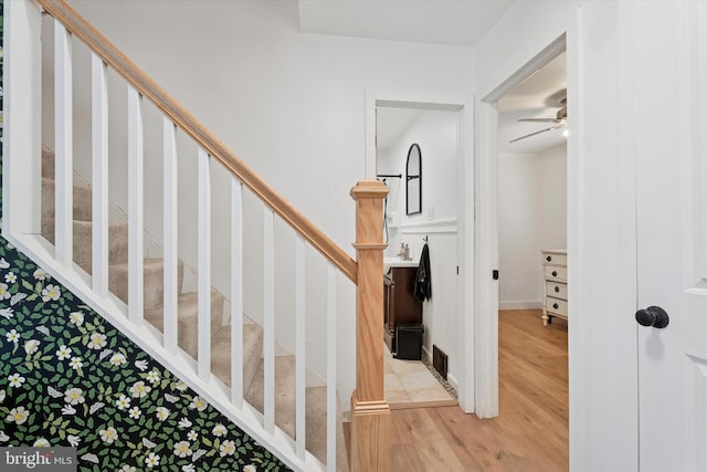 stairway featuring a ceiling fan and wood finished floors