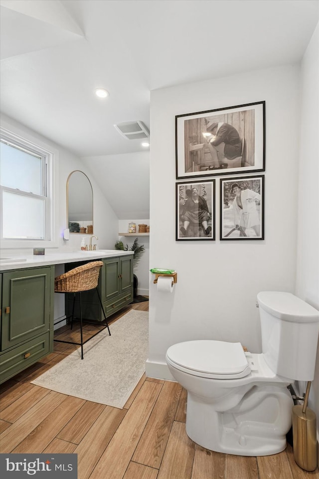 bathroom with vanity, wood finished floors, visible vents, vaulted ceiling, and toilet