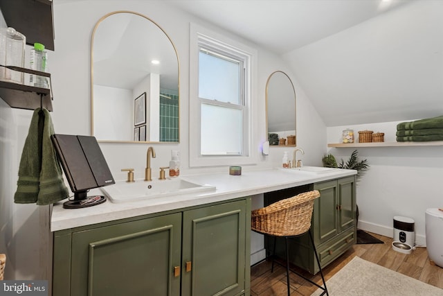 bathroom with double vanity, vaulted ceiling, wood finished floors, and a sink