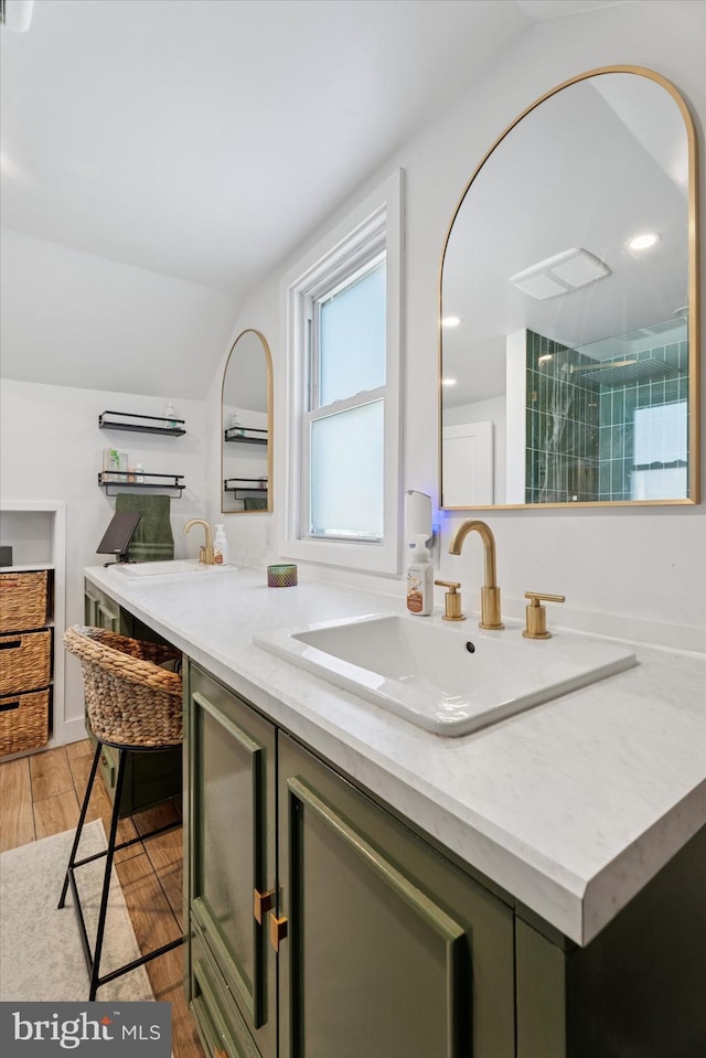 kitchen with light wood finished floors, vaulted ceiling, light stone counters, and a sink