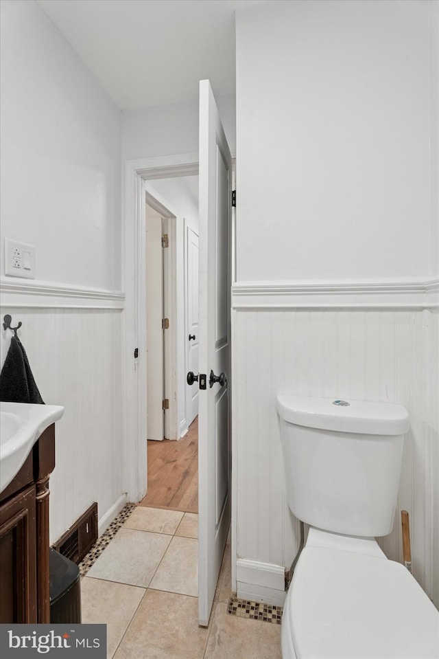 bathroom featuring tile patterned floors, a wainscoted wall, visible vents, toilet, and vanity