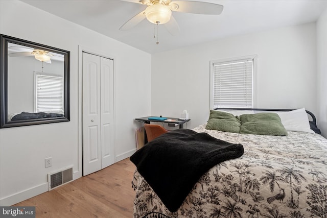 bedroom featuring a ceiling fan, wood finished floors, visible vents, baseboards, and a closet