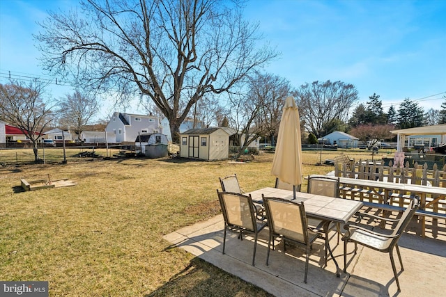 view of yard with an outbuilding, outdoor dining space, a storage shed, and fence