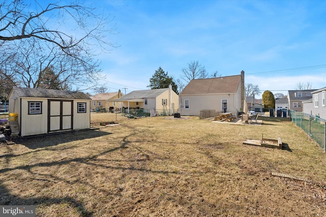 back of house with an outdoor structure, a yard, a fenced backyard, and a residential view