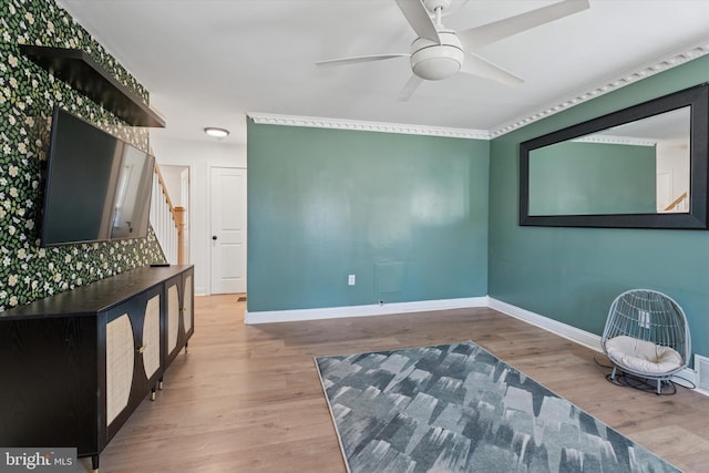 sitting room featuring stairway, wood finished floors, baseboards, and ceiling fan