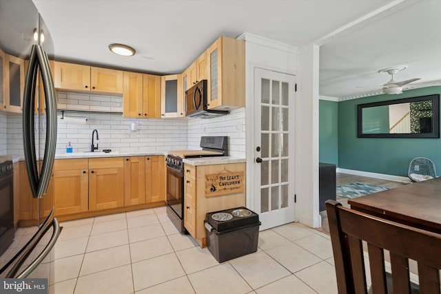 kitchen featuring light brown cabinets, light countertops, decorative backsplash, stainless steel refrigerator, and black range