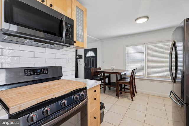 kitchen featuring light tile patterned floors, backsplash, baseboards, and appliances with stainless steel finishes