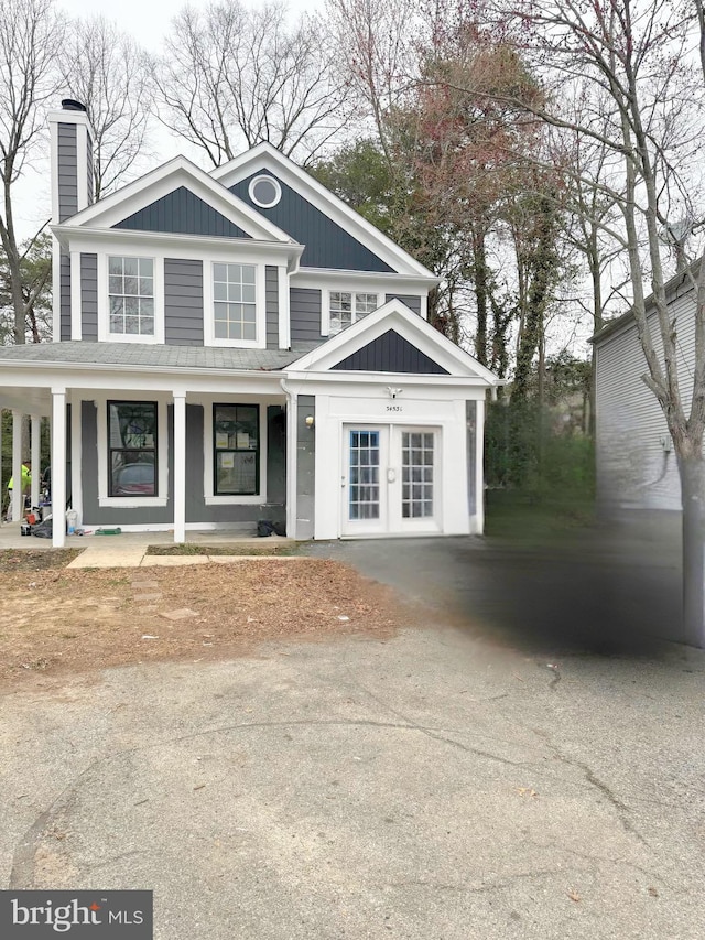 view of front facade featuring a chimney, board and batten siding, a porch, and driveway