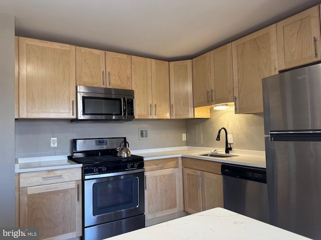 kitchen featuring stainless steel appliances, light brown cabinetry, a sink, and light countertops