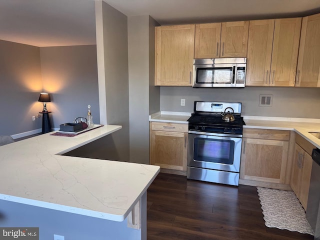 kitchen featuring light stone countertops, appliances with stainless steel finishes, dark wood-type flooring, and light brown cabinetry