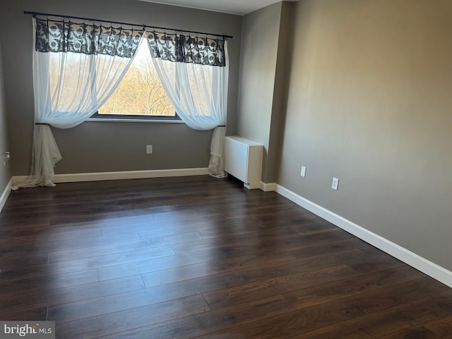 spare room featuring dark wood finished floors and baseboards