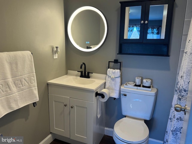 bathroom with toilet, baseboards, and vanity