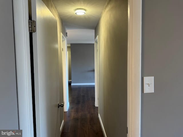 hallway featuring dark wood-style floors and baseboards