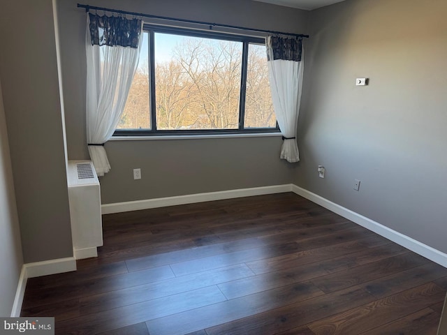 empty room featuring dark wood-style floors and baseboards