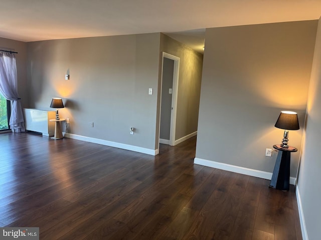 empty room with dark wood finished floors and baseboards