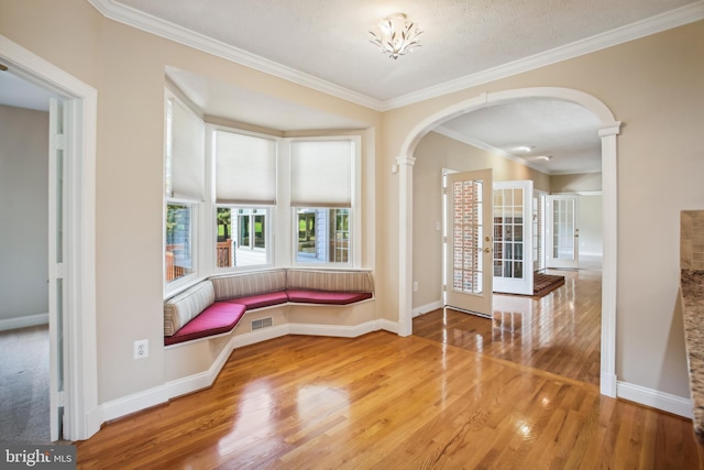 interior space with visible vents, wood finished floors, arched walkways, crown molding, and baseboards