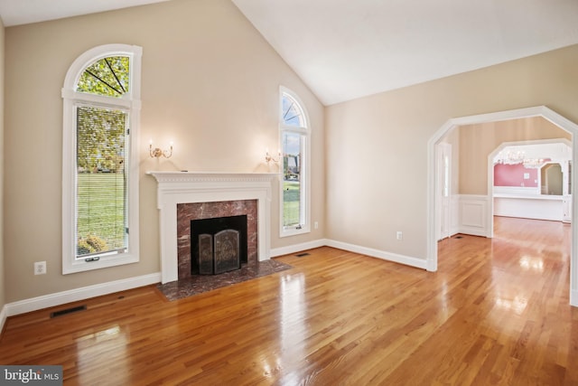 unfurnished living room with high vaulted ceiling, wood finished floors, visible vents, and baseboards