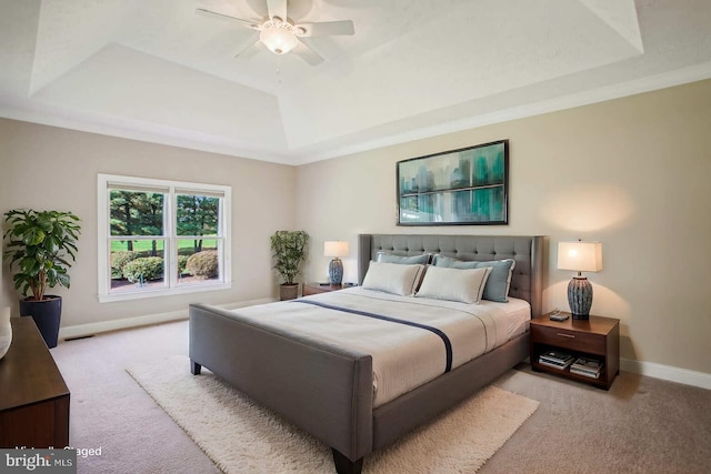 bedroom with a raised ceiling, carpet flooring, a ceiling fan, and baseboards