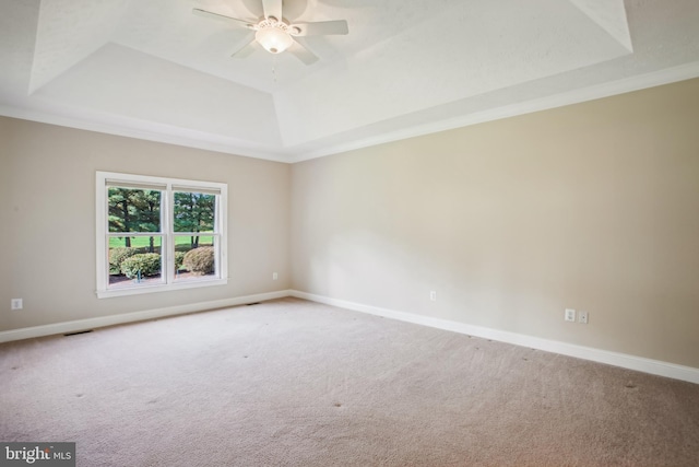 carpeted empty room featuring a raised ceiling and baseboards