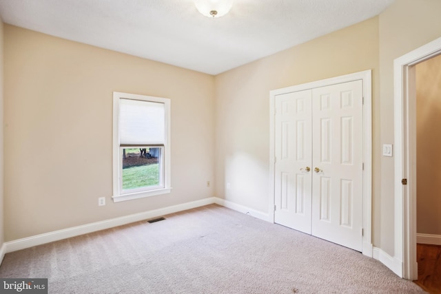 unfurnished bedroom with visible vents, baseboards, a closet, and carpet flooring