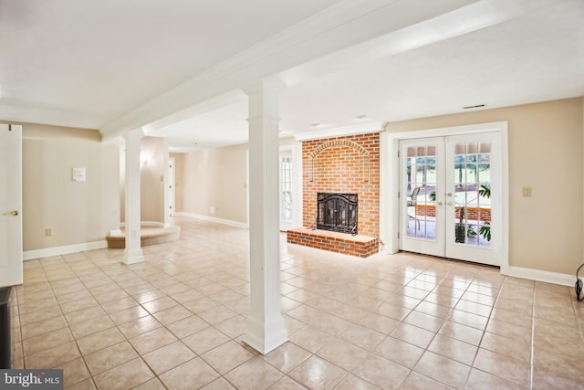 unfurnished living room featuring visible vents, baseboards, light tile patterned floors, a fireplace, and ornate columns