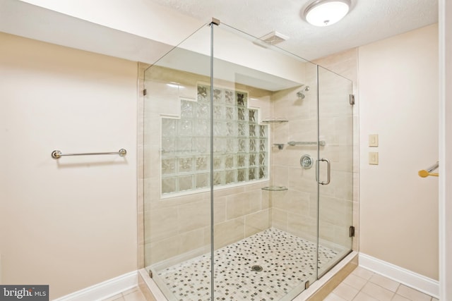 full bathroom with visible vents, a shower stall, baseboards, tile patterned floors, and a textured ceiling