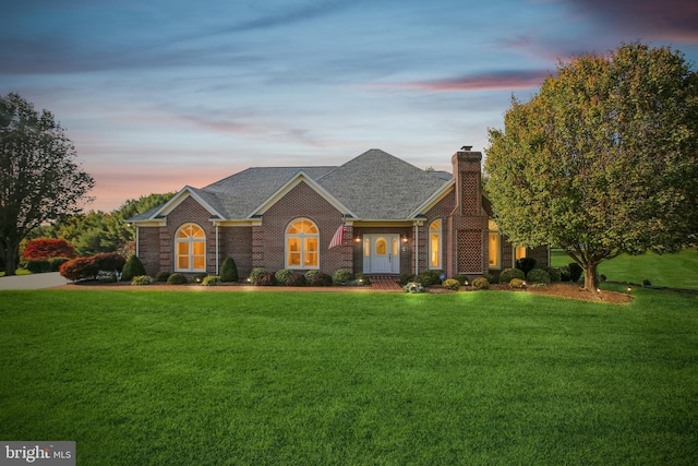 colonial home with a front lawn, brick siding, roof with shingles, and a chimney