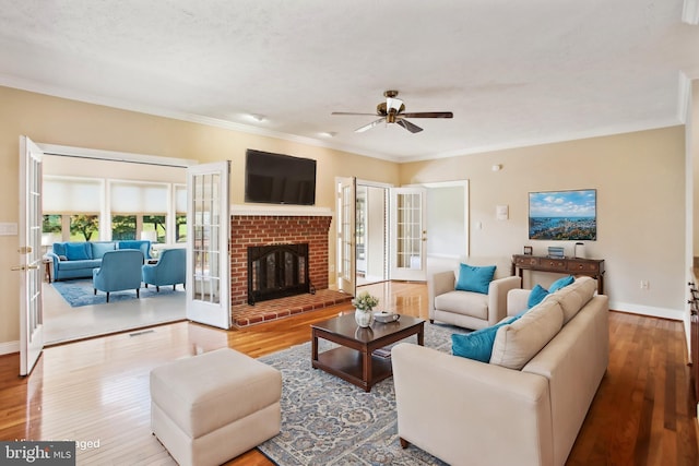 living area with wood finished floors, baseboards, ceiling fan, french doors, and crown molding