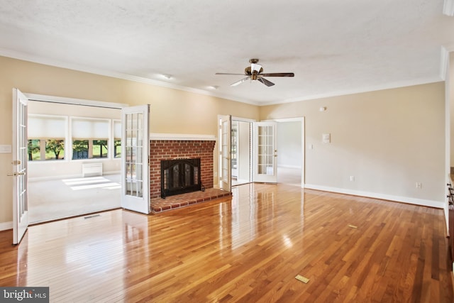 unfurnished living room with a ceiling fan, hardwood / wood-style floors, french doors, crown molding, and baseboards