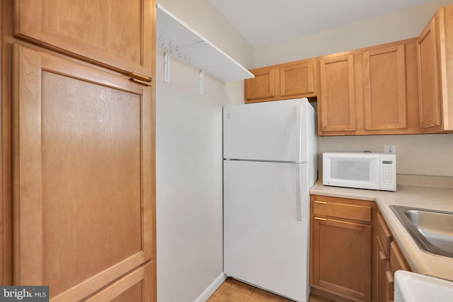 kitchen featuring light tile patterned floors, light countertops, white appliances, and a sink