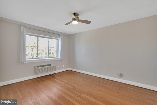 spare room featuring light wood-style floors, a ceiling fan, baseboards, and a wall mounted AC