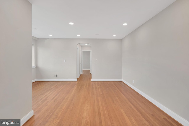 spare room with light wood-type flooring, baseboards, arched walkways, and recessed lighting