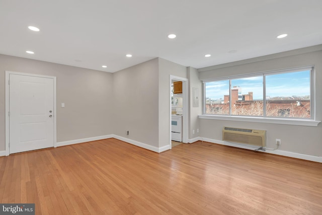 interior space featuring light wood-type flooring, a wall unit AC, and recessed lighting