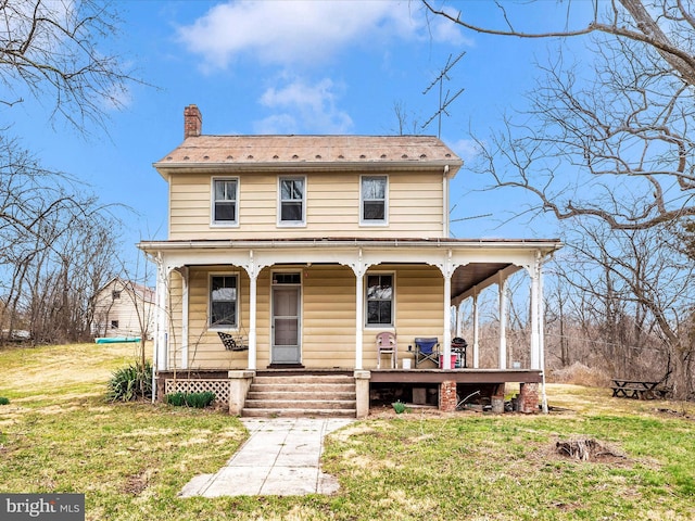 view of front of house featuring a porch, a chimney, and a front lawn