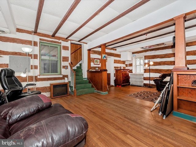 living area featuring beam ceiling, stairway, radiator heating unit, and wood finished floors