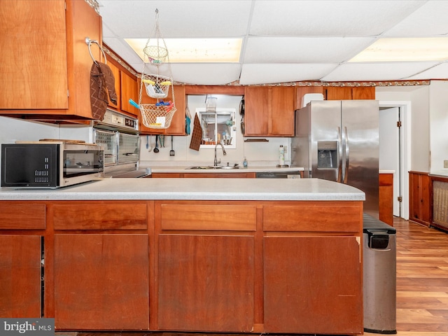 kitchen with stainless steel appliances, light countertops, light wood-style floors, and a sink