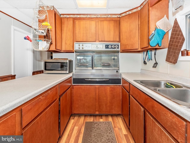 kitchen featuring wall oven, stainless steel microwave, light wood-type flooring, and light countertops