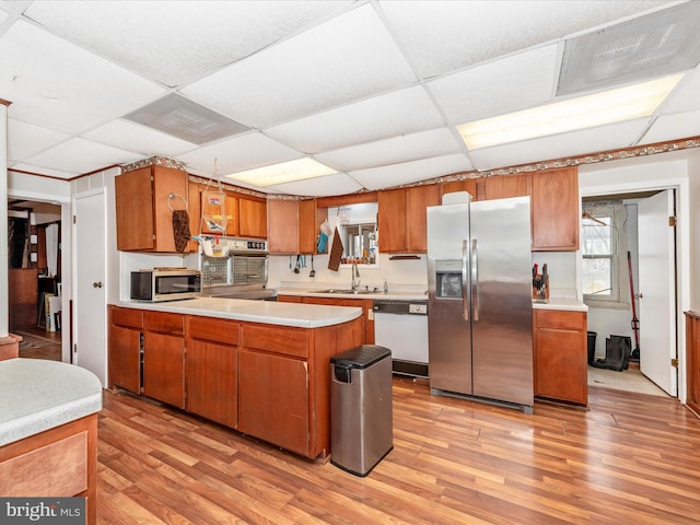 kitchen with a peninsula, light countertops, brown cabinetry, and appliances with stainless steel finishes