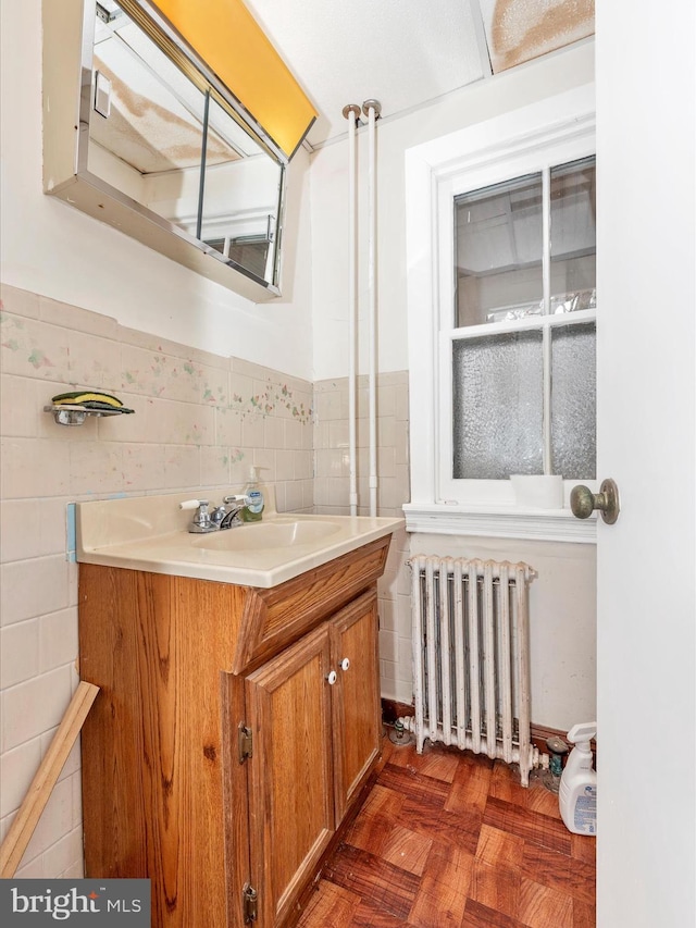 bathroom featuring a wainscoted wall, radiator, tile walls, and vanity